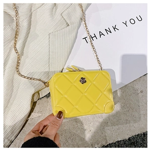 Detail of yellow quilted jelly bag with gold flower clasp and delicate metal chain strap