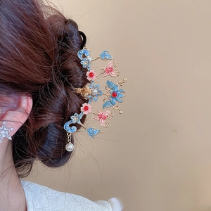 Détail d'une épingle à cheveux vintage avec papillon en émail bleu, fleurs et perles
