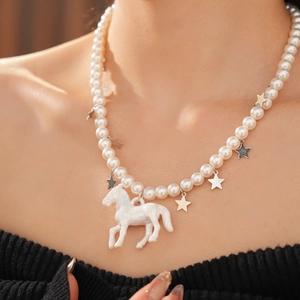 Close-up of pearl necklace featuring a white horse pendant and small metallic star charms