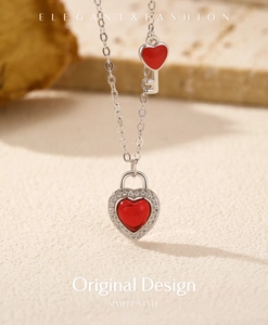 Macro shot of silver heart lock and key pendants with red enamel and pavé stones