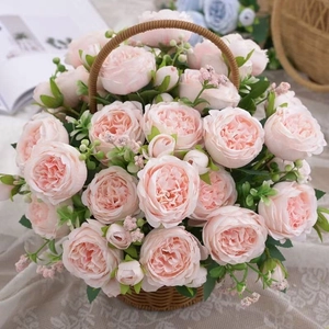 Pink artificial rose and peony silk flowers in a rustic wicker basket for home decor