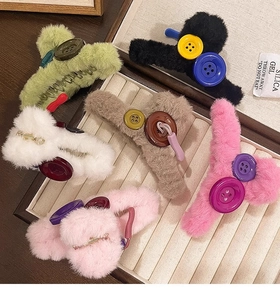 Detailed collection of six colorful plush claw clips with button accents in a wooden box