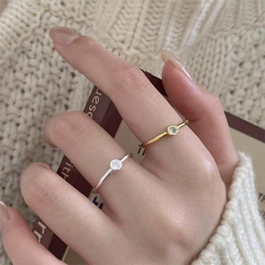 Minimalist 925 sterling silver open ring with single zircon on hand holding a book