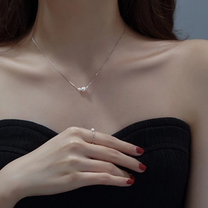 Close-up of elegant silver necklace and ring set with pearls on a model's neck and hand