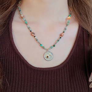 Détail d'un collier bohème avec pendentif soleil et lune sur une chaîne de perles colorées