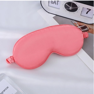 Detail of pink satin sleep mask with elastic strap and smooth silk-like texture
