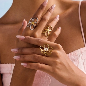 Close-up of model wearing gold and silver hollow flower rings with pearls and metal beads