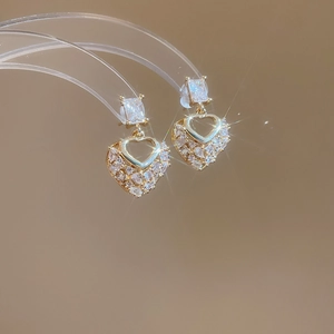 Macro shot of gold heart-shaped earrings with clear sparkling zircon stones
