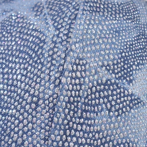 Macro detail of dark blue denim baseball cap with silver glitter and white stitching