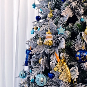 Détails d'ornements de Noël bleus et dorés incluant étoiles et cœurs sur sapin blanc