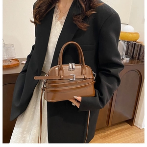 Detail of a brown leather shell bag with silver buckle and adjustable long shoulder strap