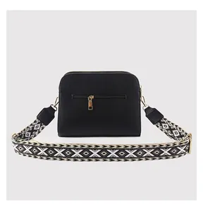 Detail view of black pebble leather crossbody bag with back zipper and woven strap