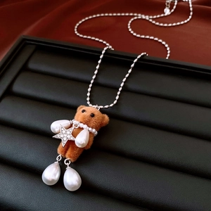 Detail of flocked bear pendant with teardrop pearls and sparkling star on silver chain