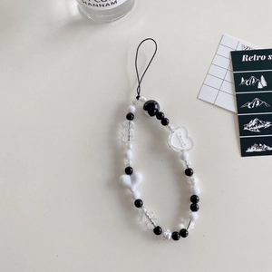 Detail of black and white beaded phone strap with love heart pendant and acrylic charms