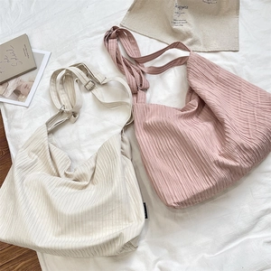 Detail view of large pleated canvas tote bags in cream and pink with wide adjustable straps