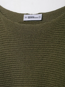 Detailed close-up of dark green ribbed knit texture with garment size label information