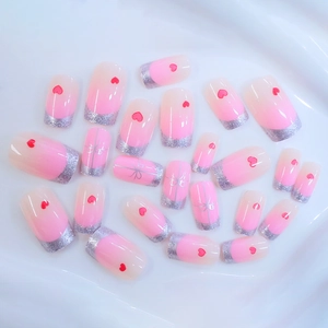Pink gradient press-on nails with silver glitter, red hearts and bow knots on white fabric