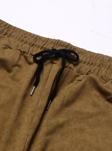 Detail of elastic waistband and black drawstring with metal tips on brown shorts