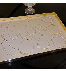 Detailed assortment of pearl and zircon flower bracelets displayed in a golden tray