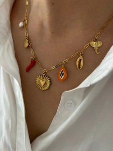 Detail of 18K gold necklace with diverse charms like seashell, heart, and pearl on model