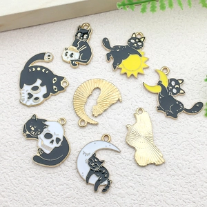 Detail of cat and skull enamel charms for DIY jewelry making with gold-plated backing