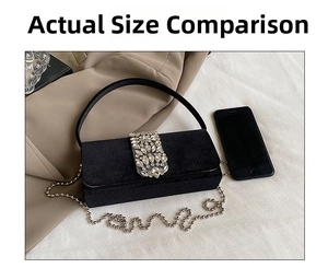 Close-up of black velvet evening bag with crystal buckle and metal ball chain strap