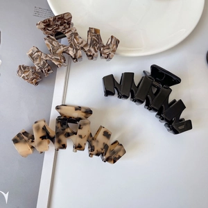 Three elegant acetate hair claws in brown marble, glossy black and tortoiseshell finishes