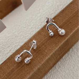 Detailed view of S925 sterling silver U-shaped earrings with pearls on wood