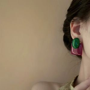 Close-up of model wearing oval green and burgundy square geometric resin earrings