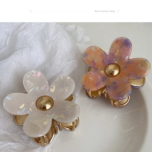 Detail of floral hair claws in pearl white and amber with gold-plated metal grip