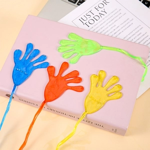 Four colorful sticky hand toys in blue green red and yellow on a pink book surface