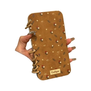 Brown faux suede iPhone case featuring tulip floral patterns and a side ring decoration