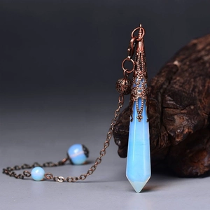 Detail of blue opal crystal pendulum with antique bronze floral metal cap on wood