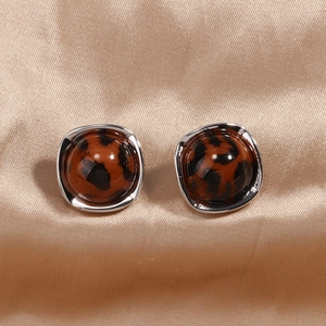 Nahaufnahme von Leopard-Resin-Ohrringen mit Silberrahmen auf champagnerfarbener Seide