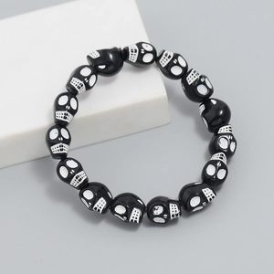 Macro detail of gothic black skull beads with polished finish on elastic bracelet