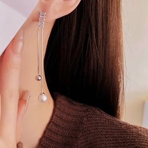 Close-up of elegant long tassel earrings with pearls and cubic zirconia on a model