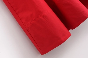 Detailed close-up of red poplin fabric showing smooth texture and fine stitching lines