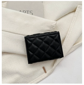 Close-up of black quilted leather mini wallet and lipstick on a minimalist background