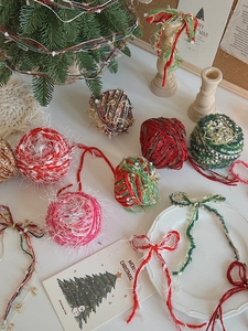 Detailed view of colorful DIY Christmas yarn balls with festive decorations on a wooden table