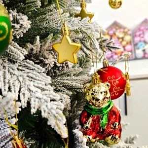Gros plan d'un ours doré et de boules colorées sur un sapin de Noël enneigé