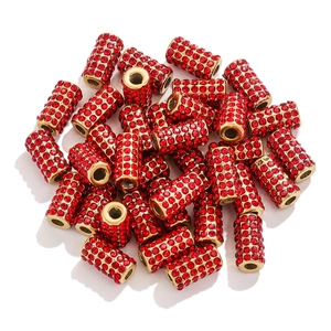 Macro detail of golden cylindrical beads with micro-paved red crystals for DIY jewelry