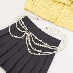 Close-up of multi-layer faux pearl body chain with golden metal on a pleated skirt