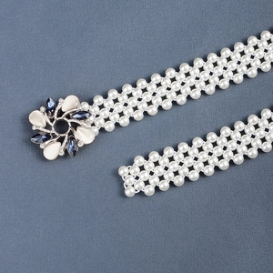 Detail of woven faux pearl belt featuring a vintage floral metal buckle with gems