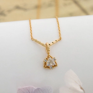 Vista macro di una collana in argento placcato oro 14K con gemma a triangolo e intaglio retro