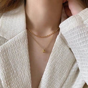 Collier double rang doré avec chaîne à billes et pendentif sphère polie sur un mannequin