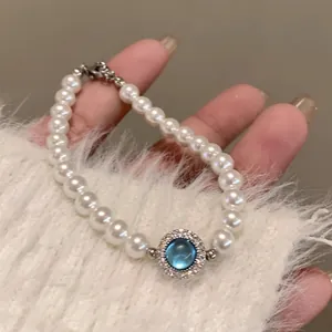 Exquisite pearl bracelet with blue gemstone and silver clasp on a cozy sweater sleeve