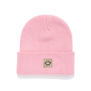 Pink knitted beanie for children with a cute smile patch for autumn and winter warmth