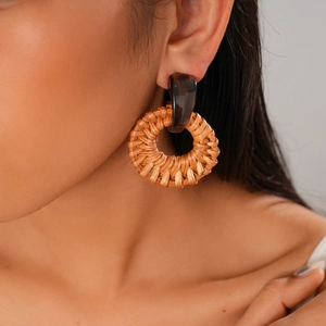 Detail shot of bohemian resin and woven rattan circular drop earrings on a model