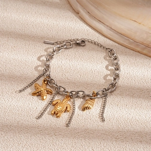 Detail of silver chain bracelet with golden sea star, turtle, and shell charms for beach style