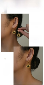Detail of gold starburst earrings with black stone inlay worn by a female model